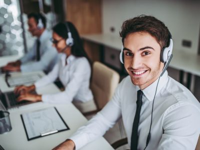 How can I help you? Beautiful call center workers in headphones are working at modern office.